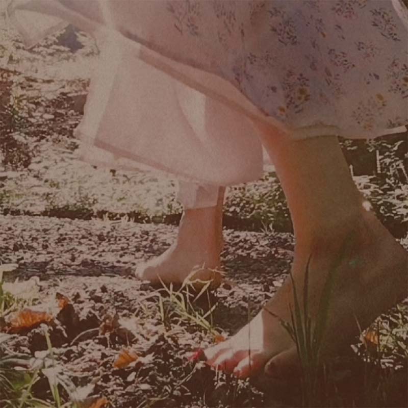 Eine Frau im Kleid geht barfuss in einem Wald
