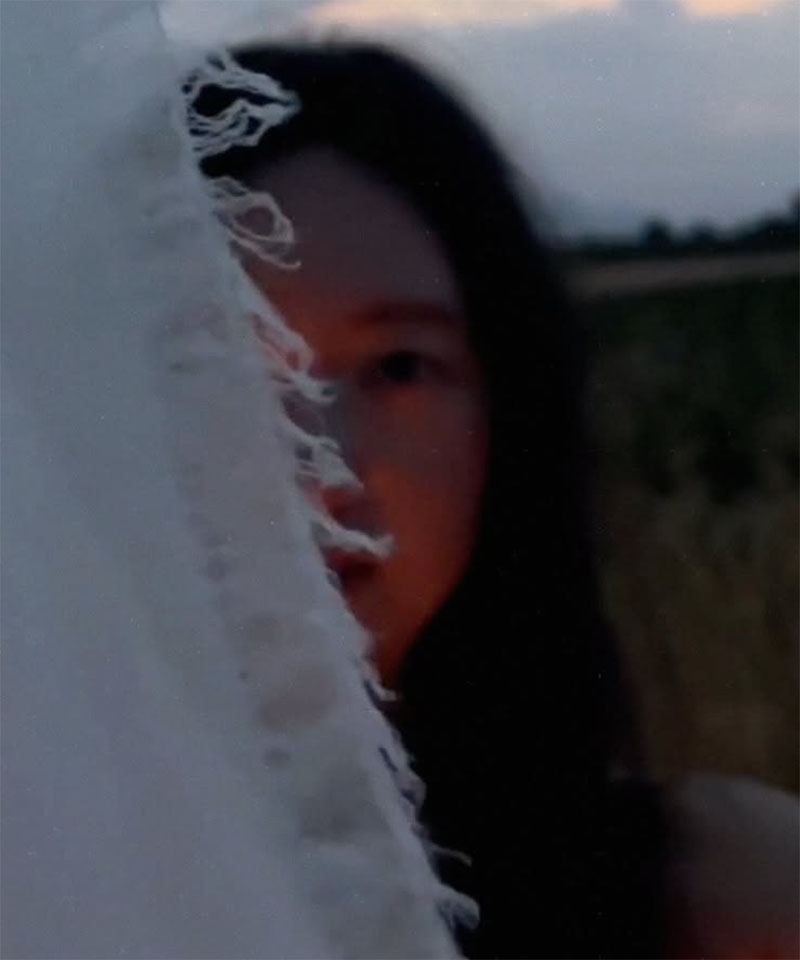 Jinyoung hinter einem Tuch im Sonnenuntergang